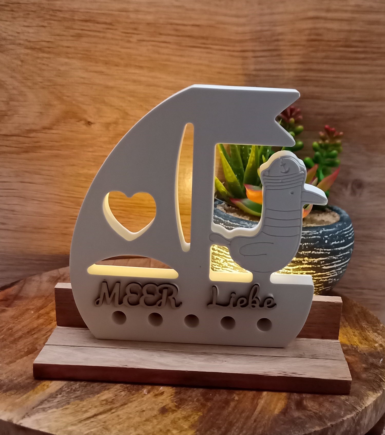 Segelboot aus Raysin mit Schriftzug und Sockel aus Holz.