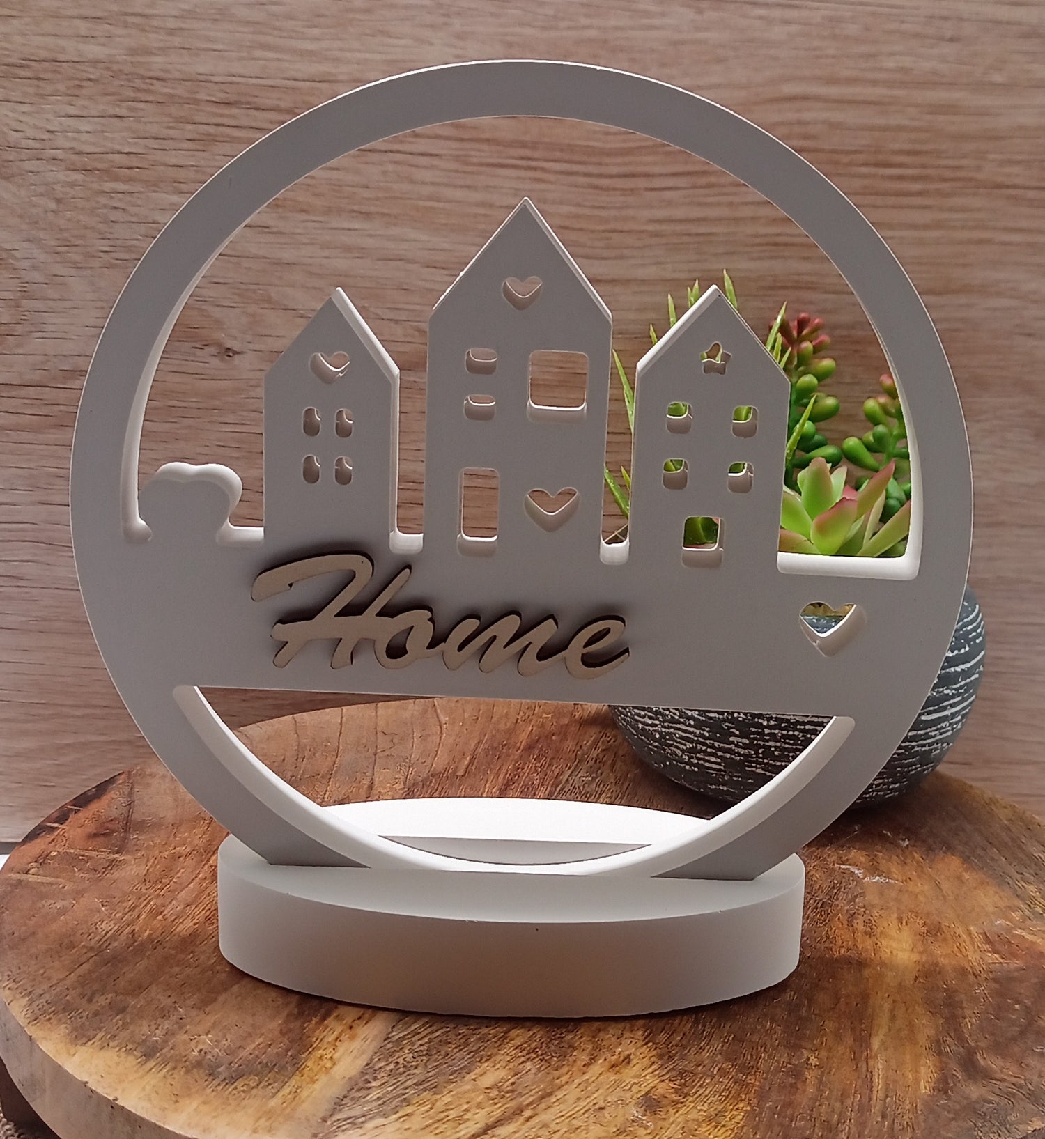 Runder Keramikaufsteller mit Hausmotiv und Sockel. Der Schriftzug Home ist aus Holz geschnitten.