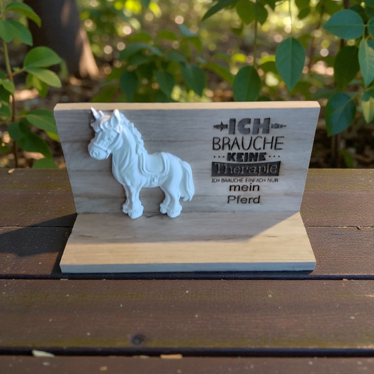 Ein Pferd aus Keramikguss auf Holzrahmen mit Therapiespruch