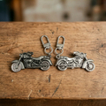 Grauer und silberner Motorrad-Schlüsselanhänger dicht nebeneinander auf einem Holztresen