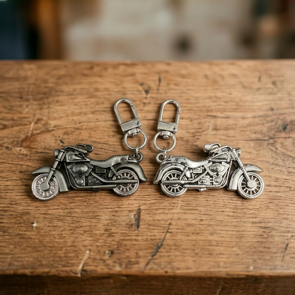 Grauer und silberner Motorrad-Schlüsselanhänger dicht nebeneinander auf einem Holztresen