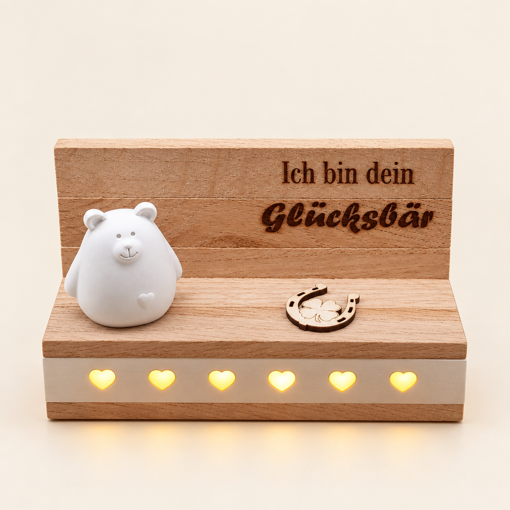 Glücksbär-Figur auf beleuchtetem Holzsockel vor hellem Hintergrund