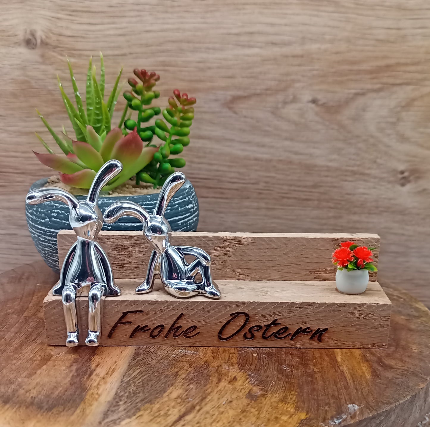 zwei silberne Osterhasen auf Holzbank