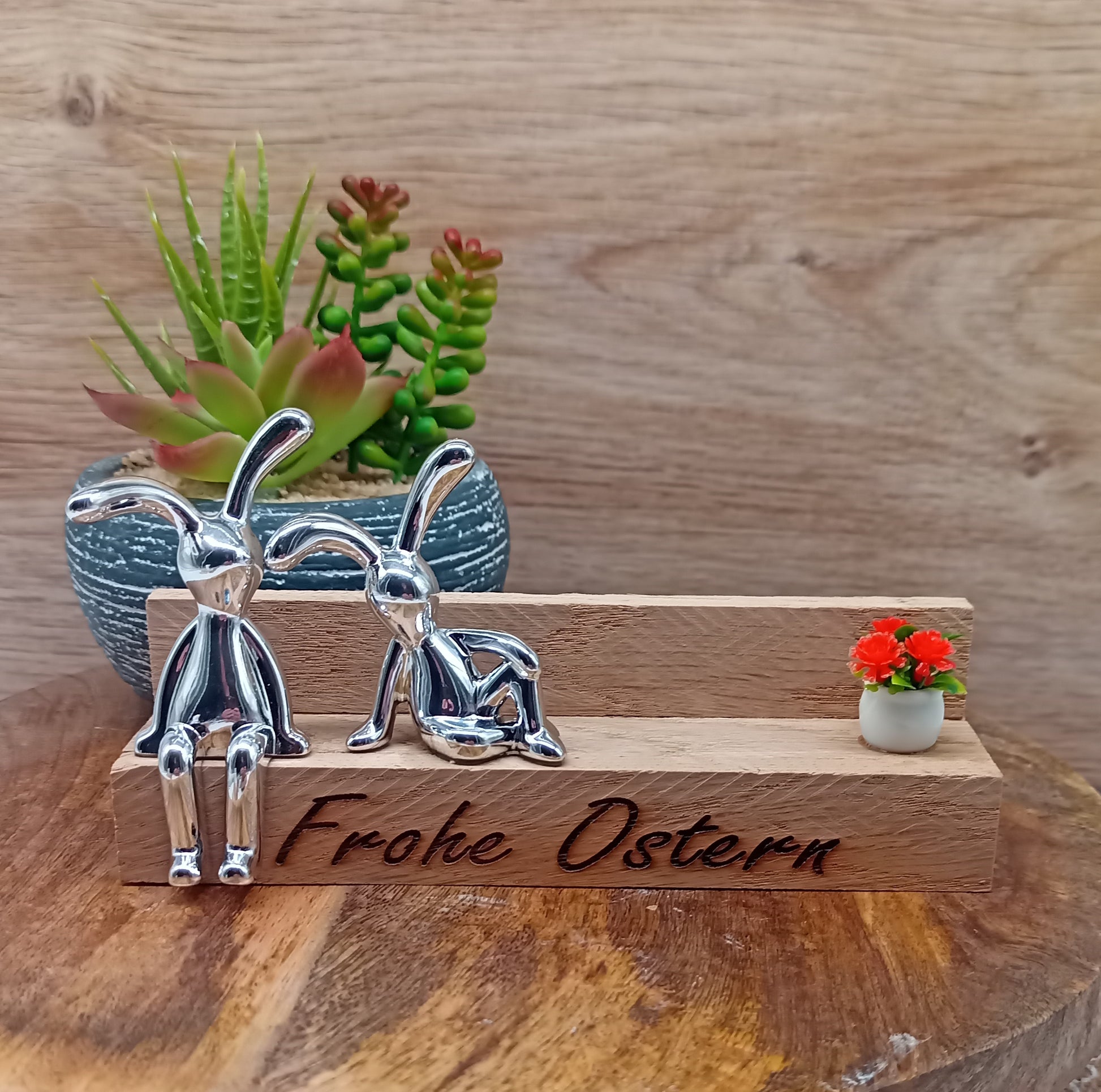 zwei silberne Osterhasen auf Holzbank